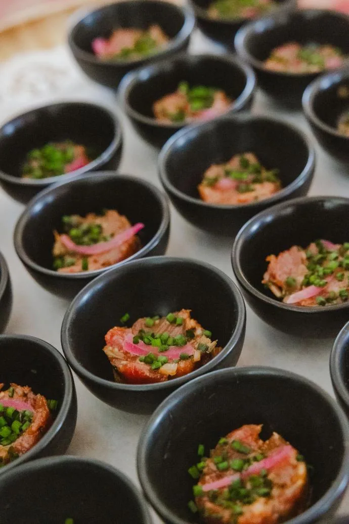 Rangées de bols noirs contenant des salades colorées garnies d'herbes fraîches