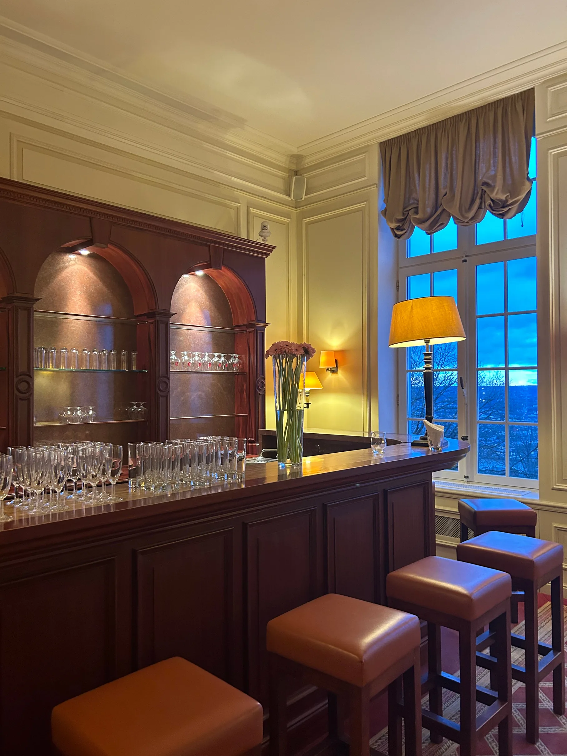 Cuisine avec armoires en bois, fenêtre bleue crépusculaire et tabouret rembourré