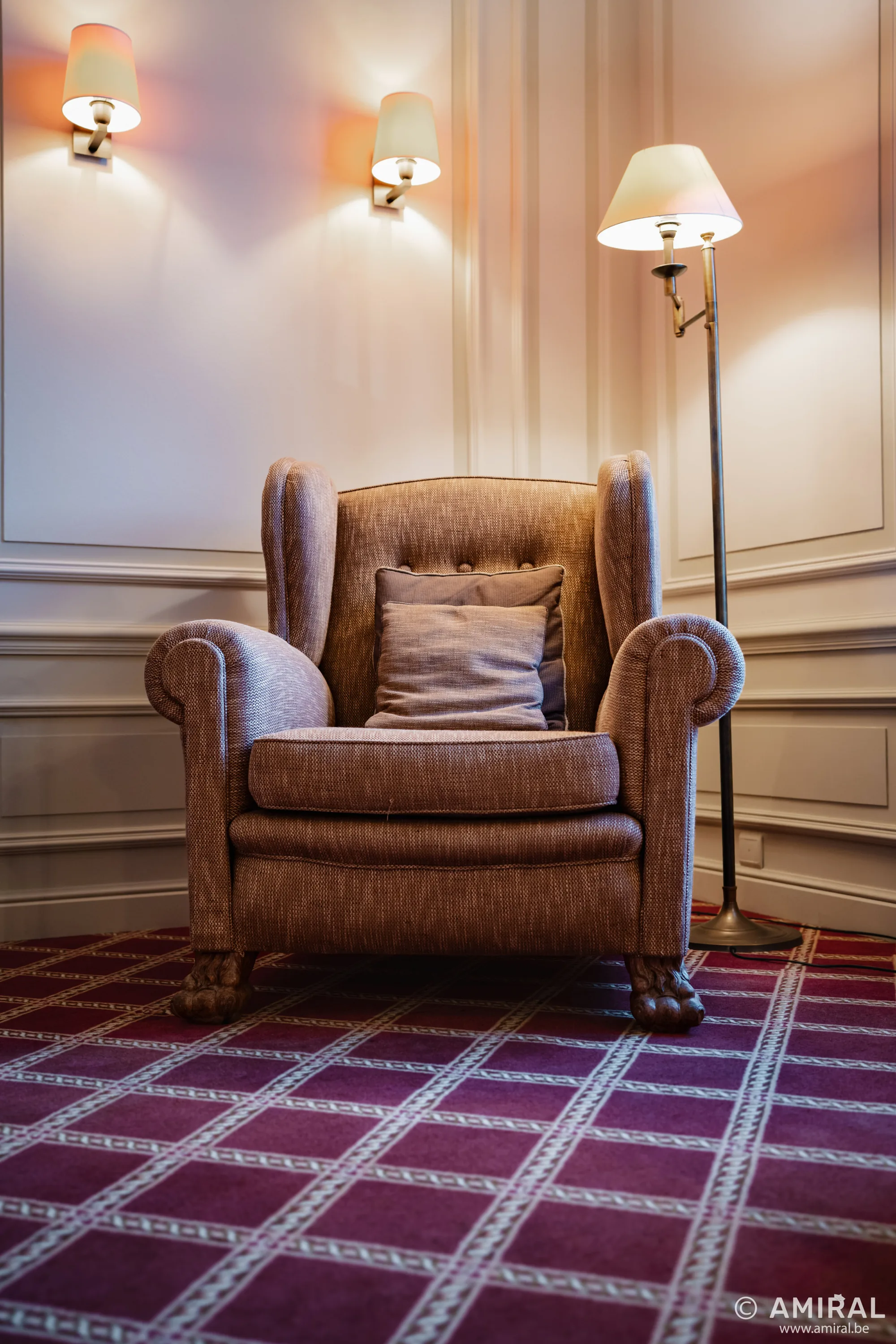 Fauteuil en cuir brun dans un salon avec lampadaire et tapis à motifs géométriques