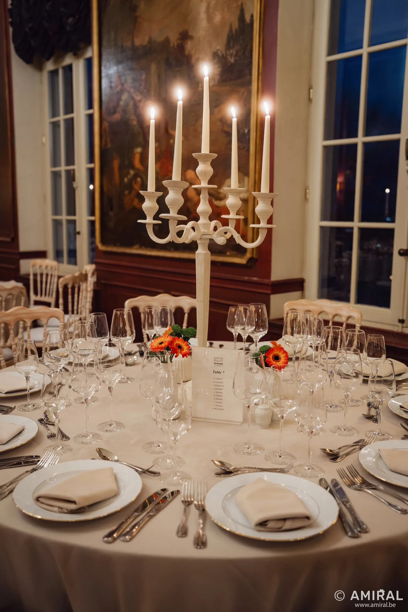 Table ronde élégamment dressée avec chandelier doré et bougies allumées pour un dîner formel
