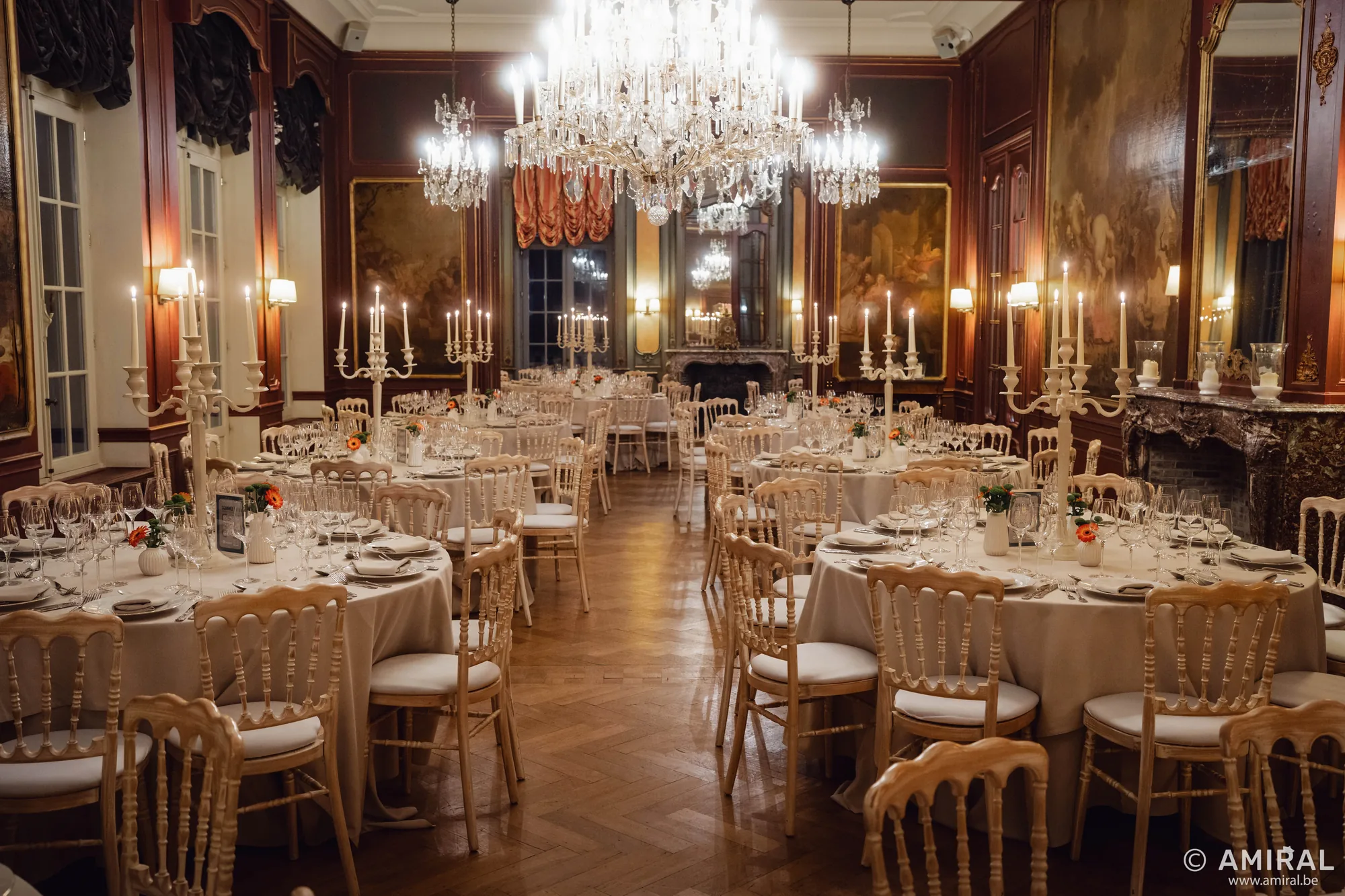 Salle de réception élégante avec tables rondes, chaises dorées et lustres en cristal