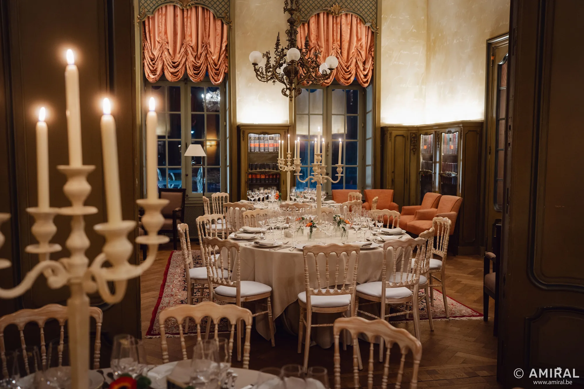 Salle à manger élégante avec table dressée, chandeliers et lustres rouges