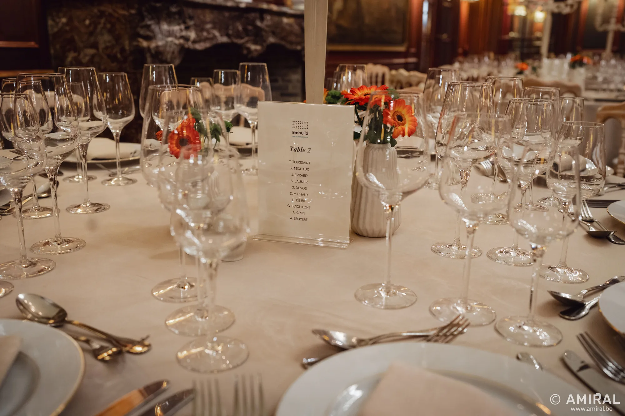 Table ronde élégamment dressée avec nappes blanches, verres à vin et centre de table fleuri