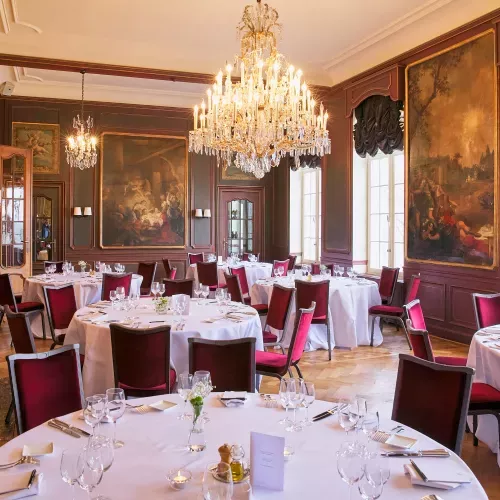 Restaurant élégant avec nappes blanches, chaises roses et lustres en cristal