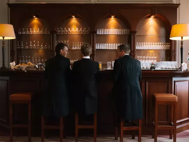 Quatre personnes assises au bar d'un établissement élégamment éclairé avec des lampes dorées