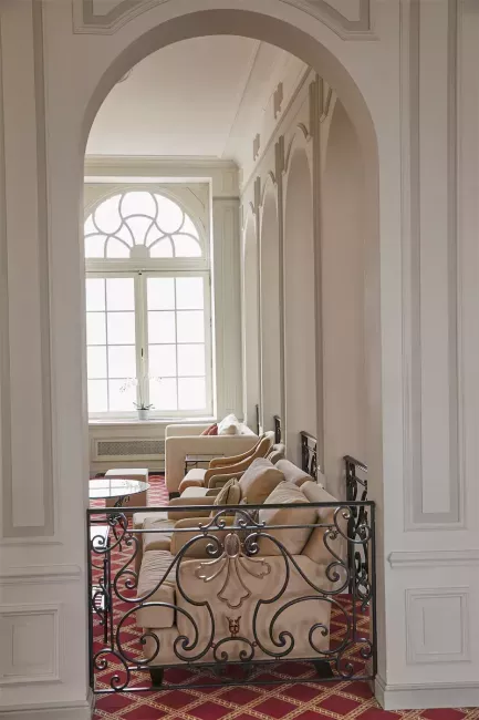 Couloir élégant avec arcades blanches, balustrade en fer forgé décorative et carrelage à motifs