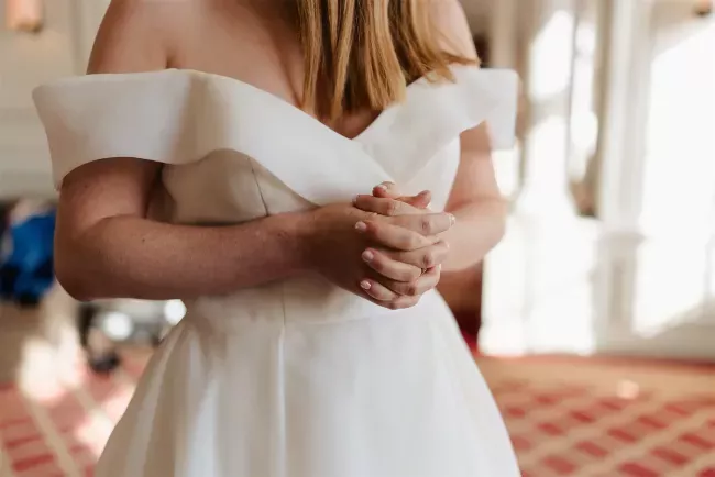 Mariée en robe blanche ajustant ses mains devant elle